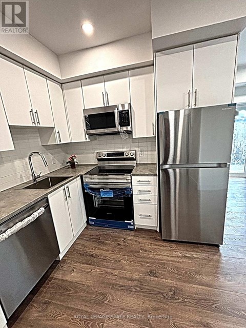 A kitchen with white cabinets and a wood floor.