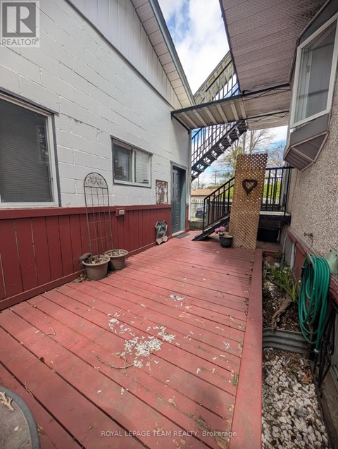 A red wooden deck with a metal railing and a small garden area.