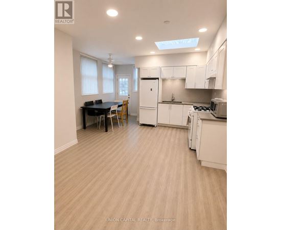 A kitchen with white cabinets and a dining table with chairs.