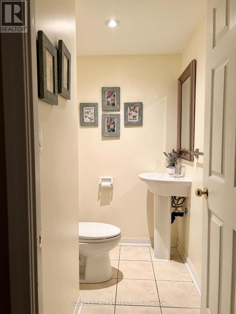 A bathroom with a toilet, sink and pictures on the wall.