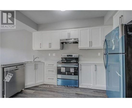 A kitchen with white cabinets and a black fridge.
