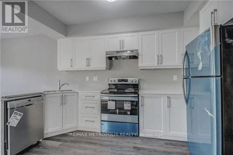 A kitchen with white cabinets and a black fridge.