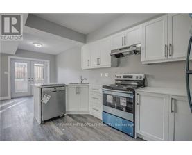 A kitchen with white cabinets and a fridge.