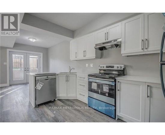 A kitchen with white cabinets and a fridge.