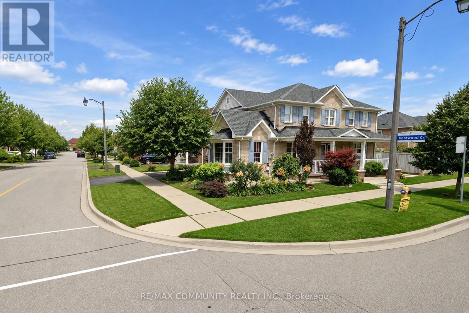 A street view of a residential area with houses and a RE/MAX Community Realty Inc. sign.