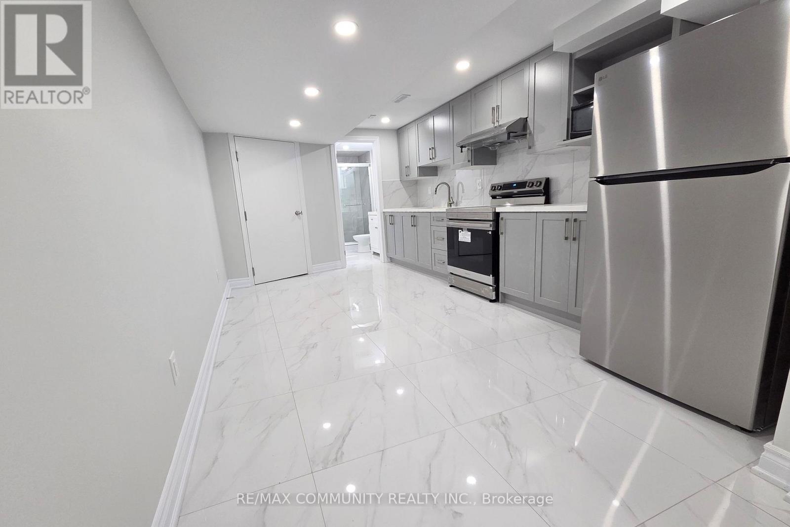 A modern kitchen with a stainless steel refrigerator and marble flooring.