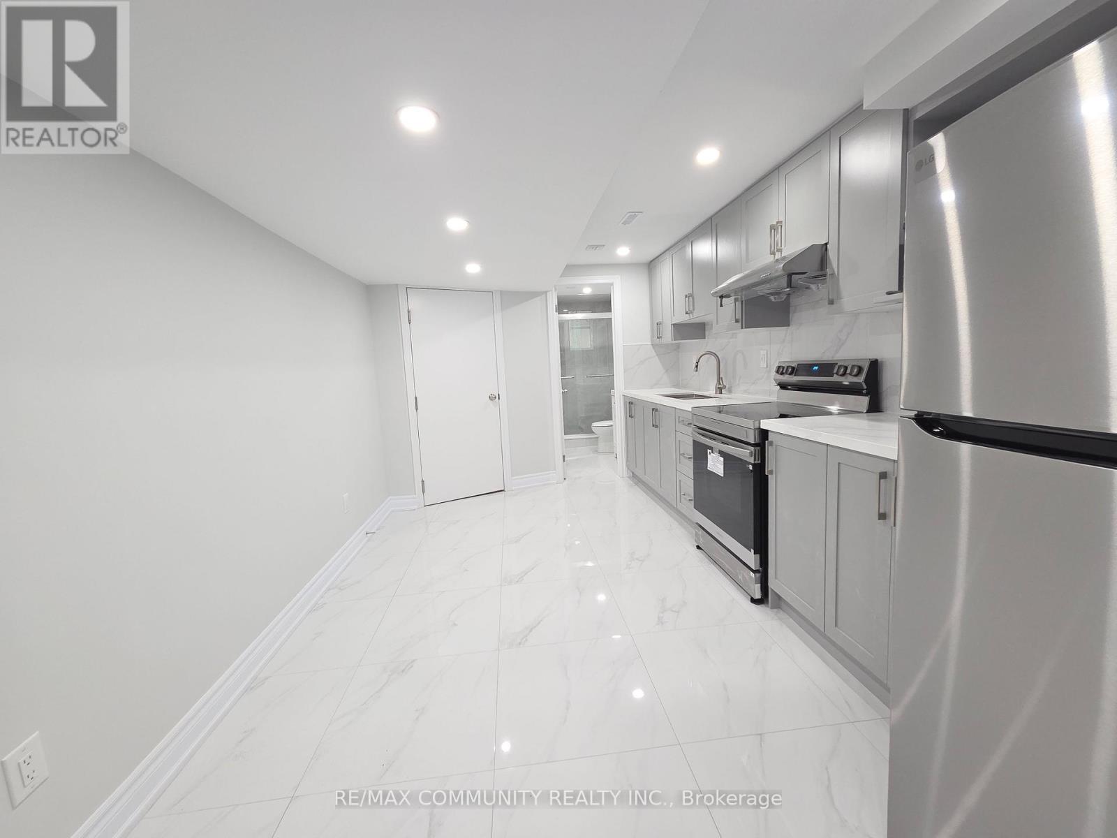 A modern kitchen with stainless steel appliances and white marble flooring.