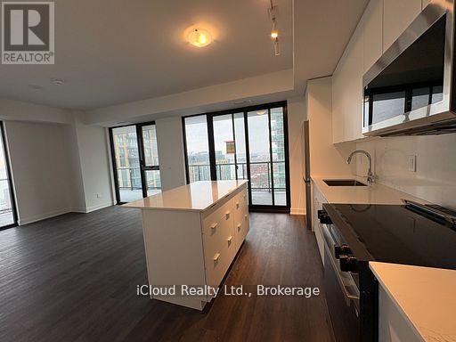A modern kitchen with dark wood floors and white cabinetry.