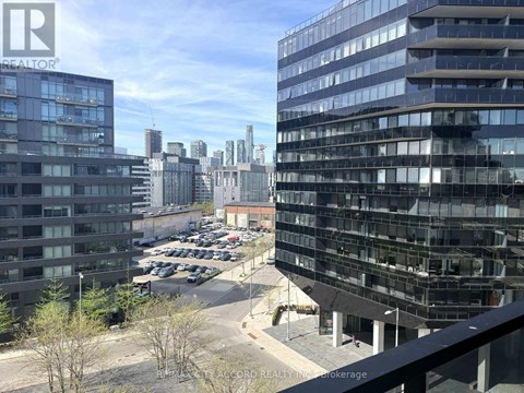 A view of a cityscape with buildings and cars from a balcony.