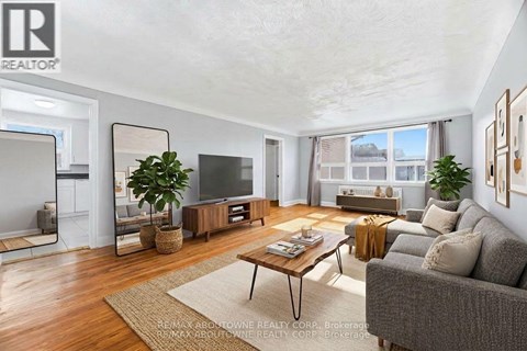 A living room with a grey couch, a wooden coffee table, and a large window.