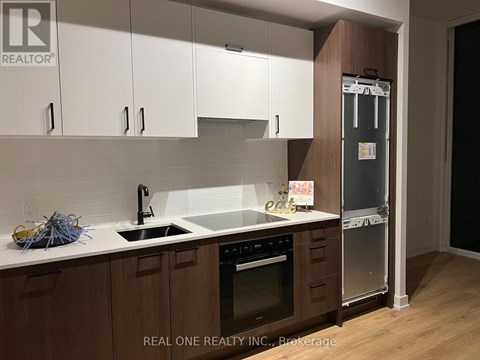 A kitchen with white cabinets and a black fridge.