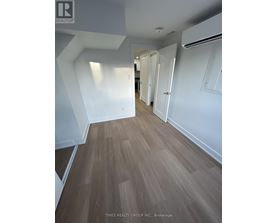 A hallway with wood flooring and white walls.