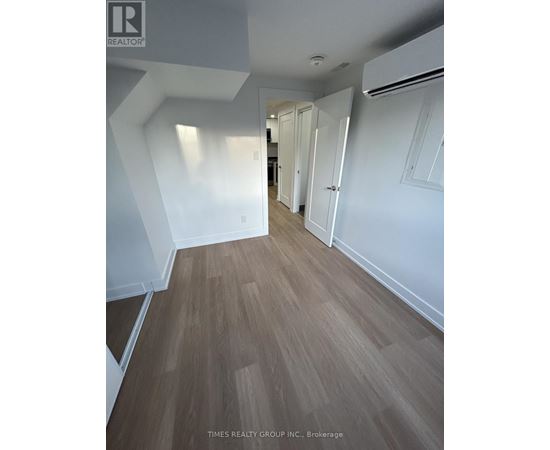 A hallway with wood flooring and white walls.