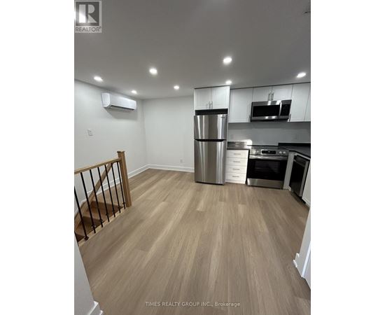 A kitchen with a refrigerator, microwave, and oven.