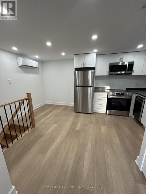 A kitchen with a refrigerator, microwave, and oven.