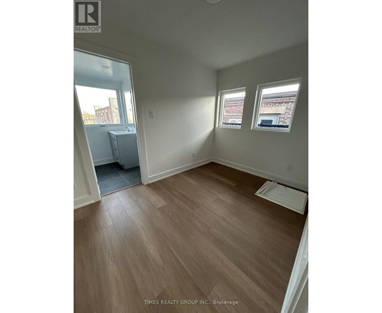 A room with wooden flooring and two windows.