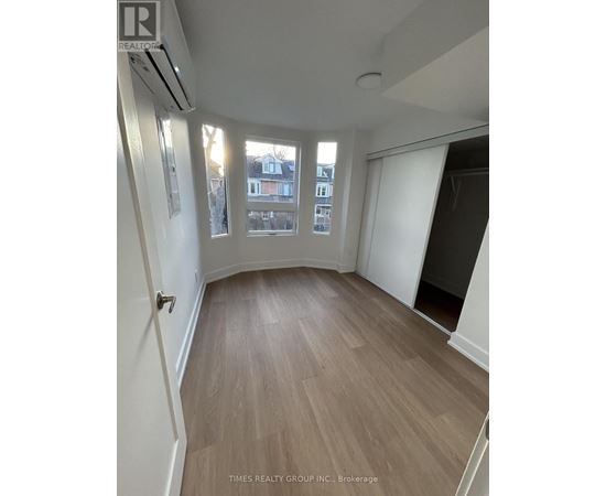 A room with wooden flooring and a window overlooking a building.