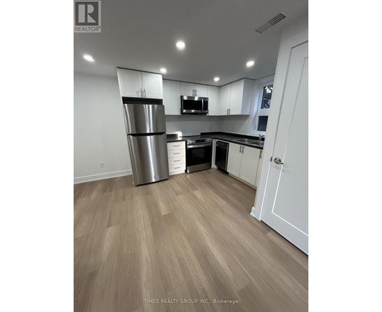 A kitchen with a refrigerator, microwave, and cabinets.