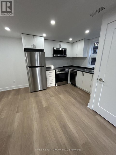 A kitchen with a refrigerator, microwave, and cabinets.