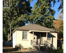 A small house with a porch and a tree in front.