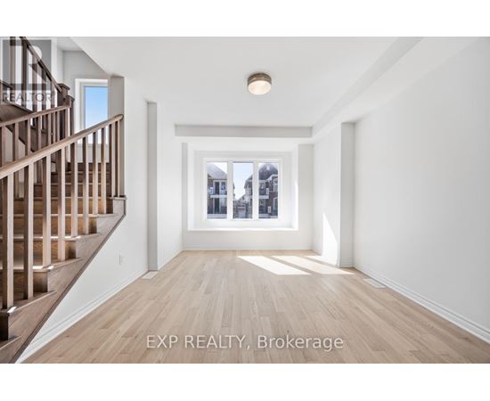 A spacious room with wooden floors and a staircase on the left side.