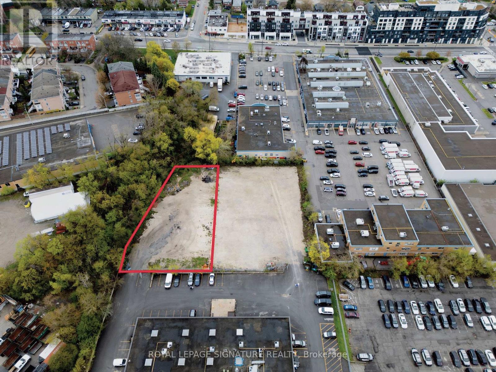 An aerial view of a parking lot with a red outline indicating a property for sale.