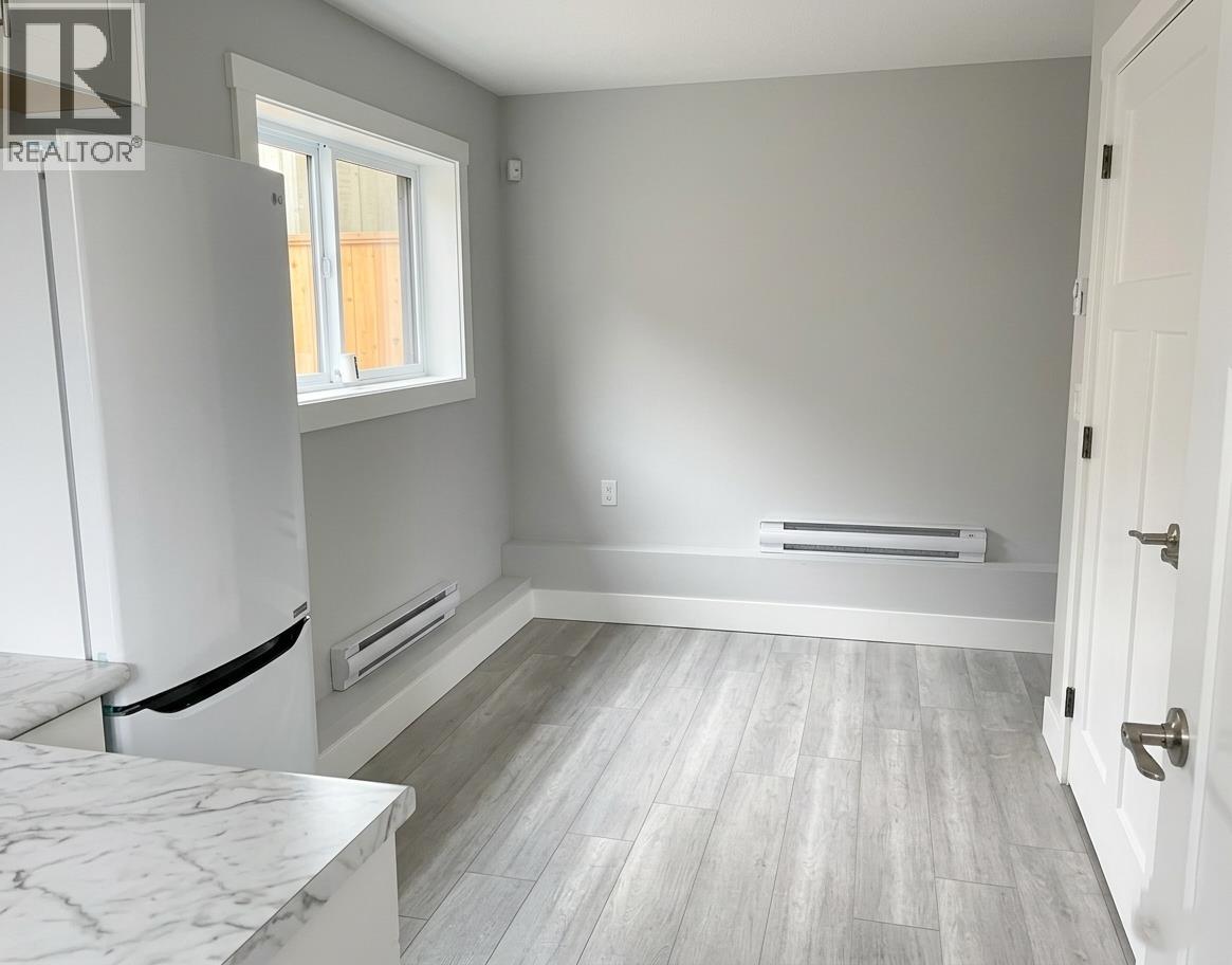 A white kitchen with a marble countertop and a window.