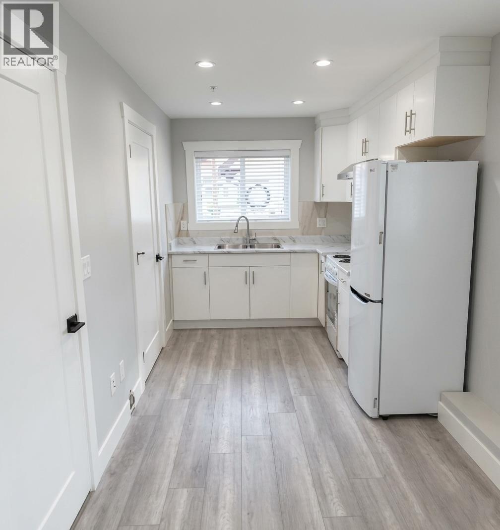 A white kitchen with a refrigerator on the right.