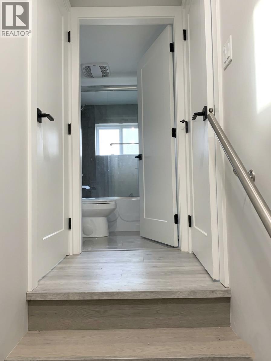 A white doorway leads to a bathroom with a toilet and sink.