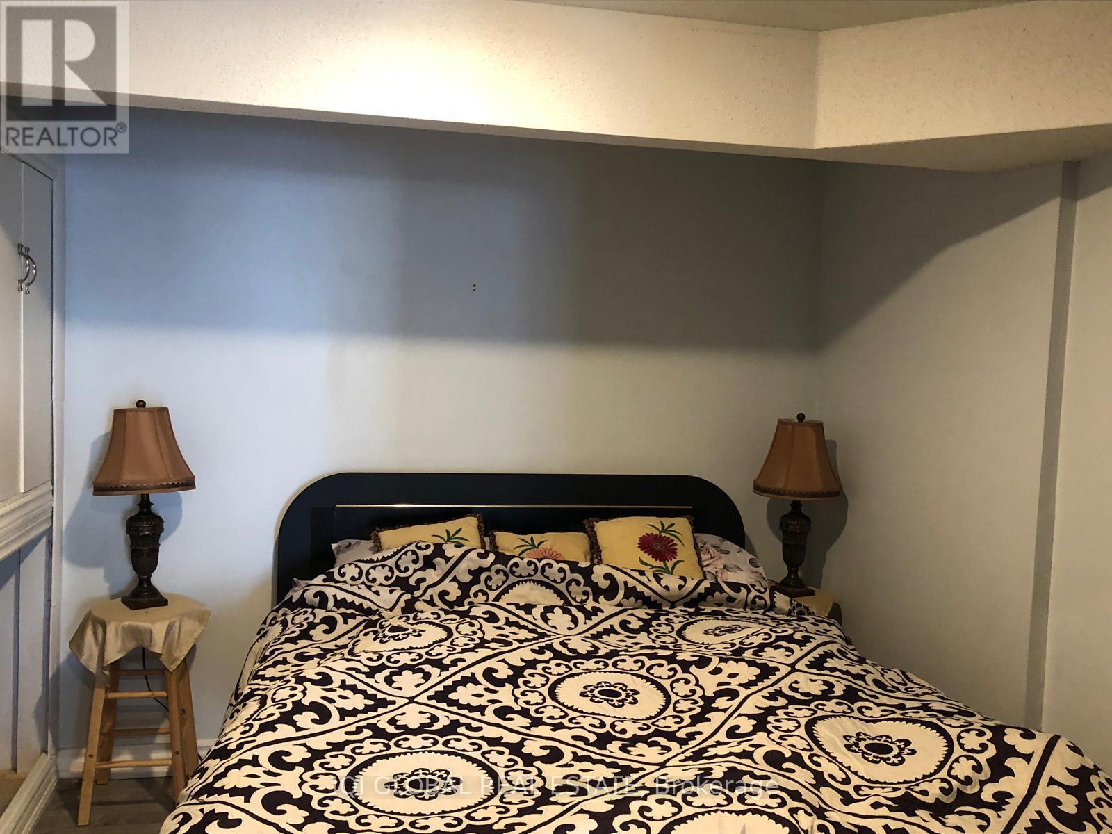 A bed with a black and white patterned comforter sits in a room with two lamps on either side.