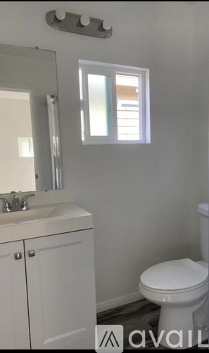 A white toilet in a bathroom with a sink and mirror.