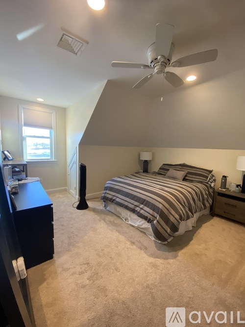 A bedroom with a bed, dresser, and ceiling fan.
