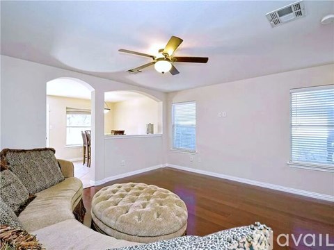 A living room with a beige couch and a round ottoman.