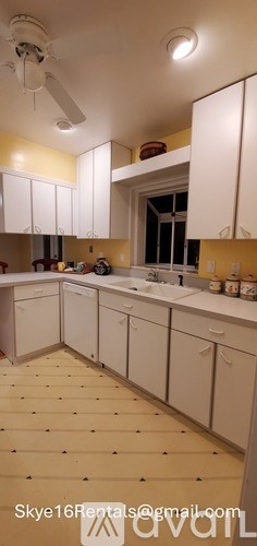 A kitchen with white cabinets and a ceiling fan.
