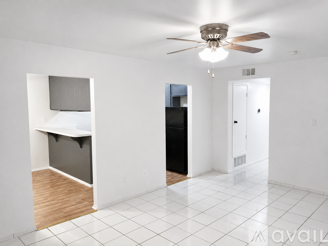 A spacious room with a ceiling fan and a black refrigerator.