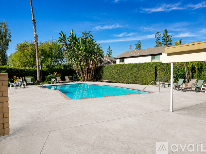 A pool surrounded by a concrete patio and a white fence.