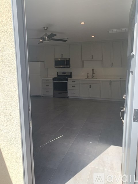 A kitchen with white cabinets and a fan on the ceiling.