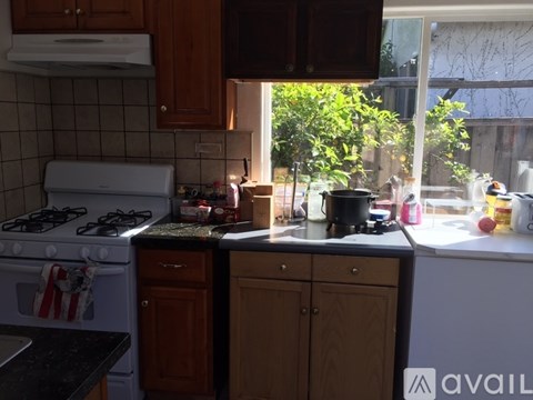 A kitchen with a white stove top and wooden cabinets.