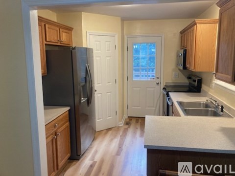 A kitchen with wooden cabinets and a black refrigerator.
