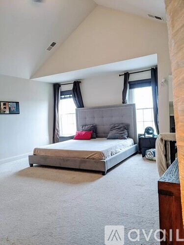 A bedroom with a large bed and a window with curtains.