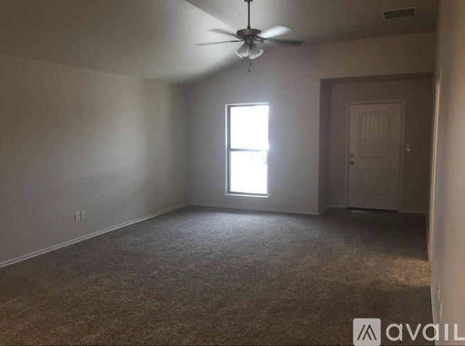 A room with a carpeted floor, a ceiling fan, and a window letting in natural light.