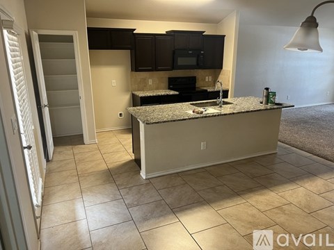 A kitchen with granite countertops and black cabinets.