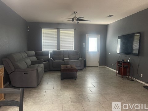 A living room with a grey sofa set and a ceiling fan.