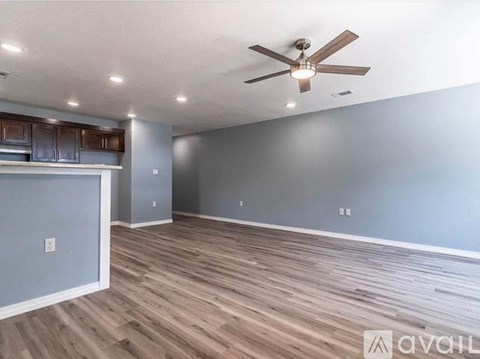 A spacious room with a ceiling fan and wooden flooring.