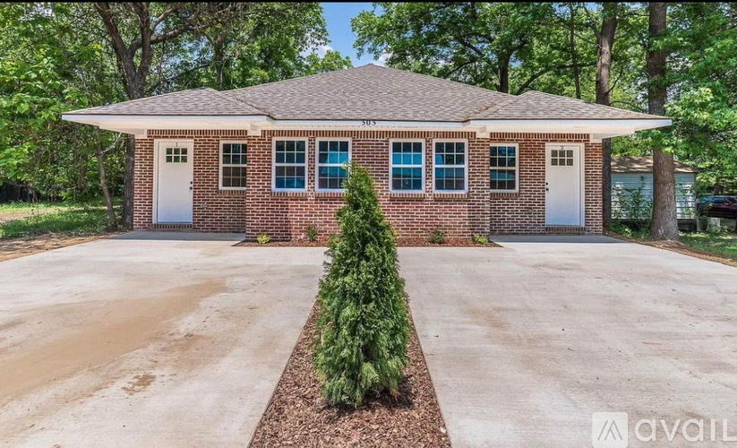 A house with a driveway and a small tree in front.