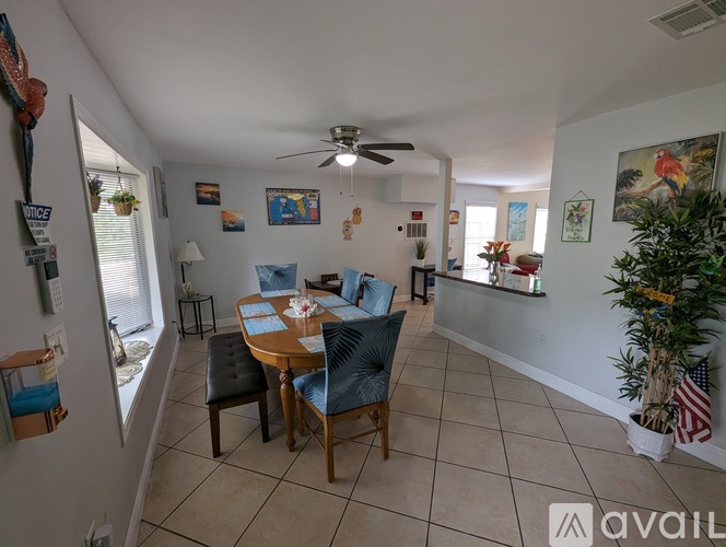 A dining room with a table set for four and a ceiling fan.
