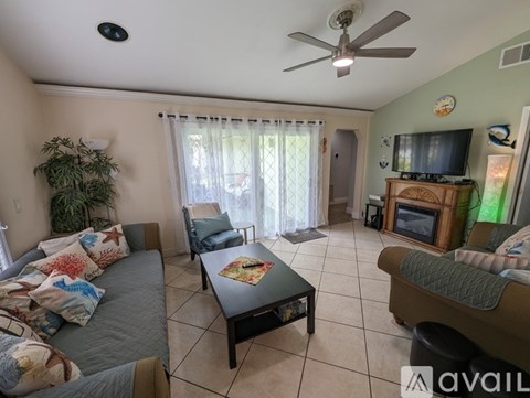 A living room with a grey couch, a black coffee table, and a television on a wooden stand.