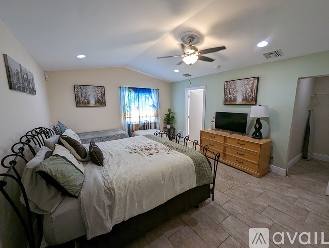 A bedroom with a bed, dresser, and ceiling fan.