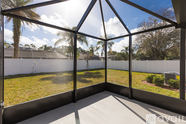 A sunny day in a glass-walled room with a view of a lawn and trees.