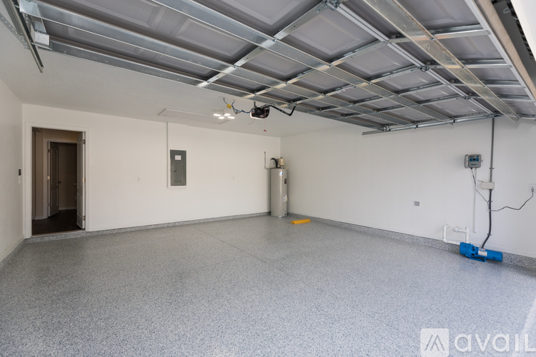 A spacious room with a ceiling covered in ductwork and a single light fixture hanging from the ceiling.